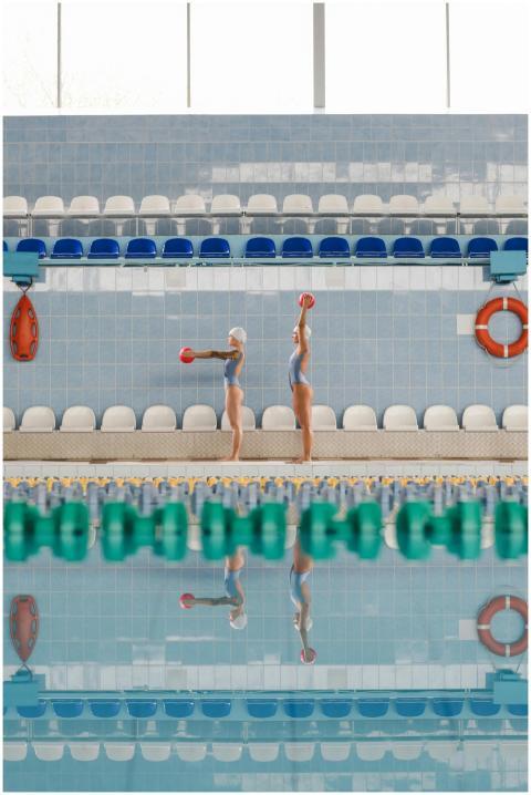 Two synchronized swimmers practice with balls in a