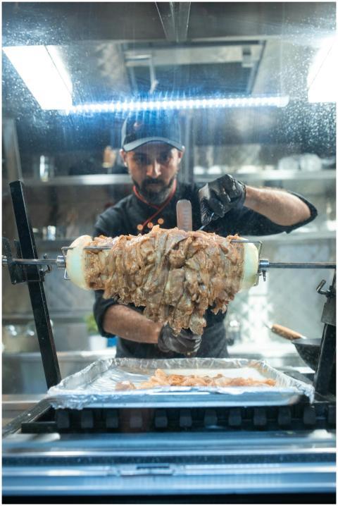 Chef adeptly cuts shawarma meat slices in a bustli