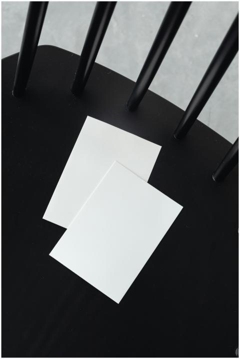 Two blank sheets of paper rest on a black chair pr