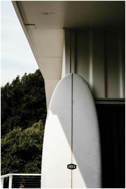 White surfboard leaning against a modern building