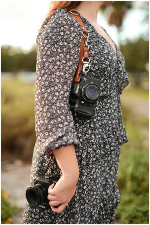 Female photographer holding DSLR cameras in a flor