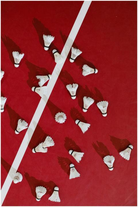 A top-down view of shuttlecocks scattered on a red