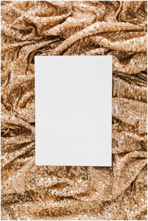A plain white paper on shimmering gold sequin fabr