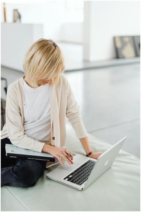 Blonde woman sitting casually using a laptop indoo