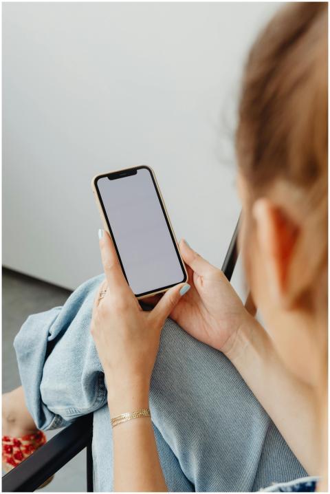 Woman sitting indoors using a smartphone with a bl