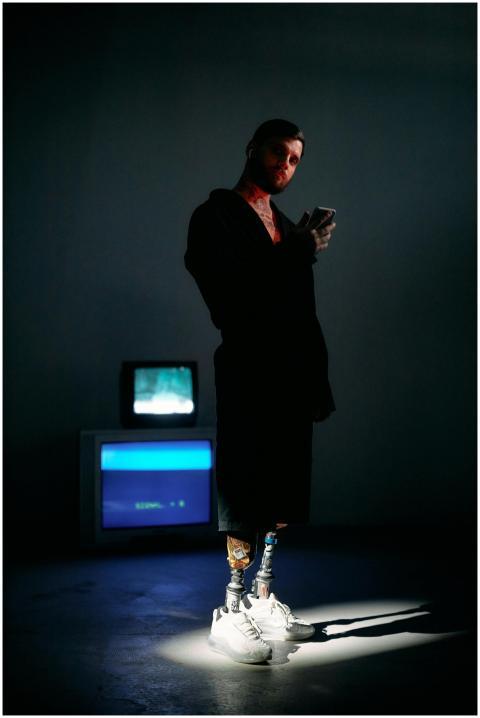 Man in a dimly lit studio wearing a bathrobe, usin