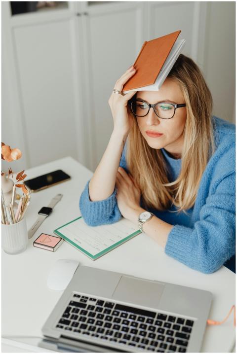 Thoughtful woman with glasses in blue sweater hold