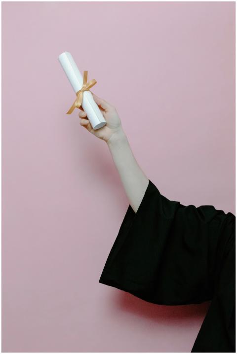 Hand of a graduate wearing a gown holding a diplom