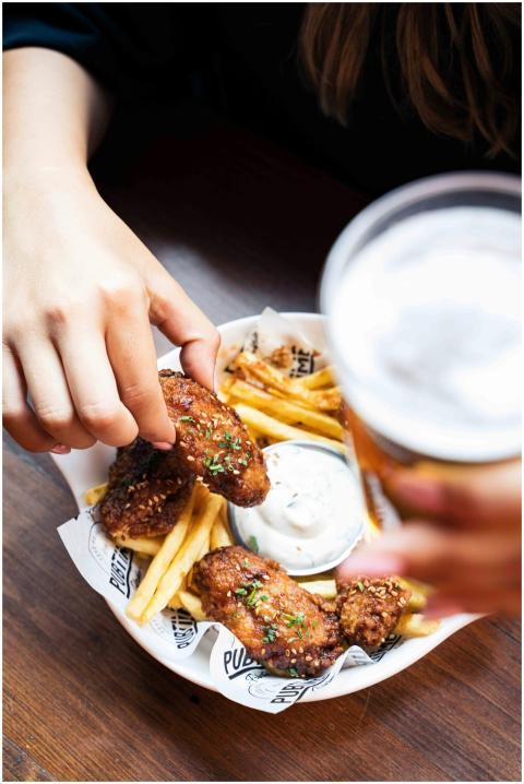 Close-up of hands holding fried chicken and fries