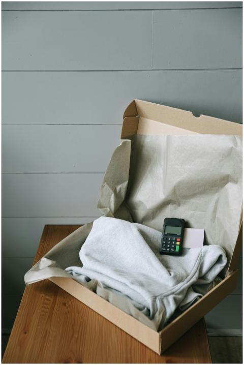 Cardboard box containing a folded shirt and a paym