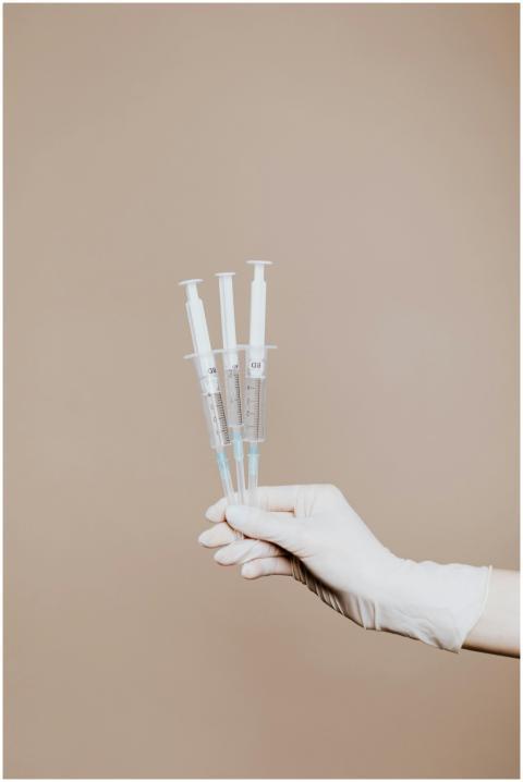 Gloved hand holding sterile syringes for medical u