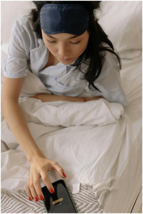 Asian woman in sleepwear using smartphone on bed w