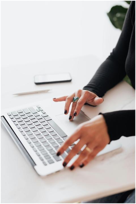 A businesswoman's hands typing on a laptop at a br