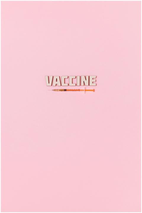 Creative vaccine text and syringe on pastel pink b