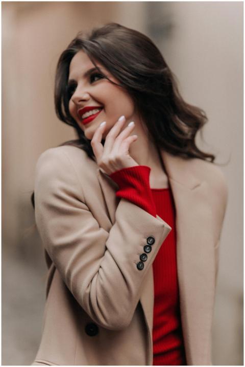 Smiling woman in a beige coat and red sweater, exu