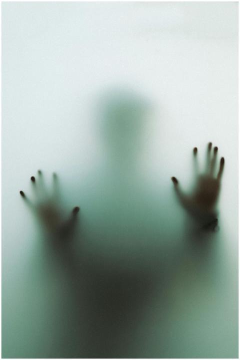Eerie silhouette of a person behind frosted glass