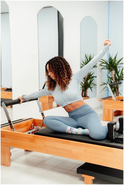Woman with curly hair exercising on a pilates refo