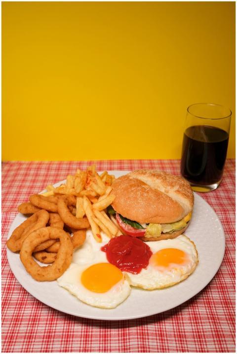 A hearty breakfast plate featuring a burger, eggs,