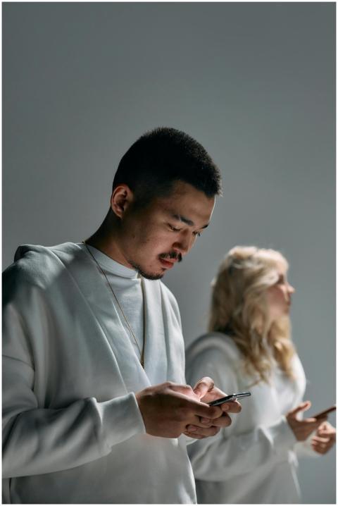 Two young adults focused on their smartphones, emb