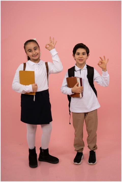 Two happy schoolchildren in uniform pose with book