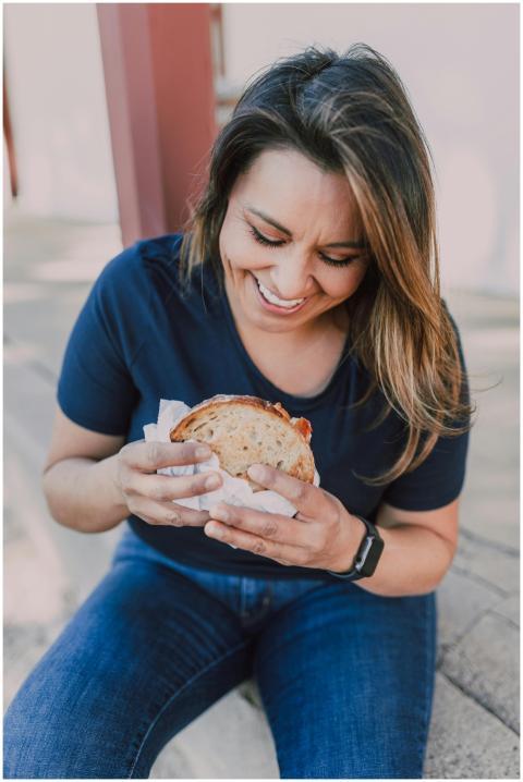 Smiling woman enjoys a sandwich outdoors, capturin