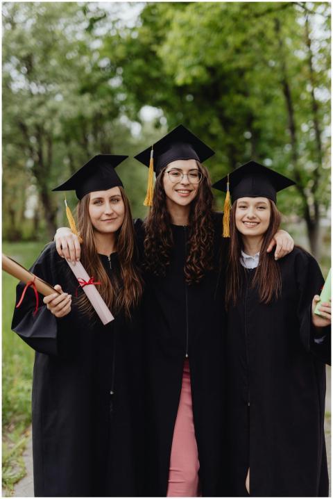 Three female graduates in caps and gowns celebrati