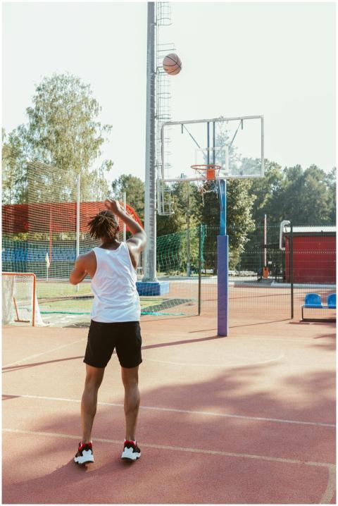 Adult man shooting a basketball into the hoop on a