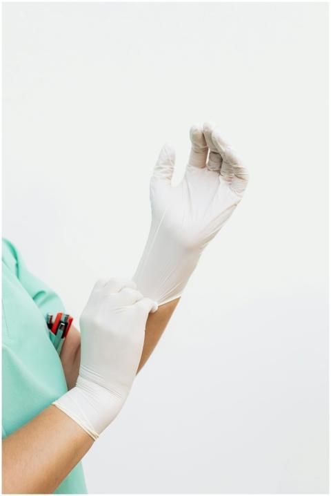 A healthcare worker in green scrubs wearing white