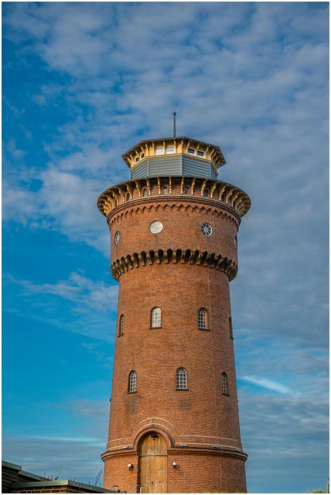 A historic red brick water tower under a clear blu
