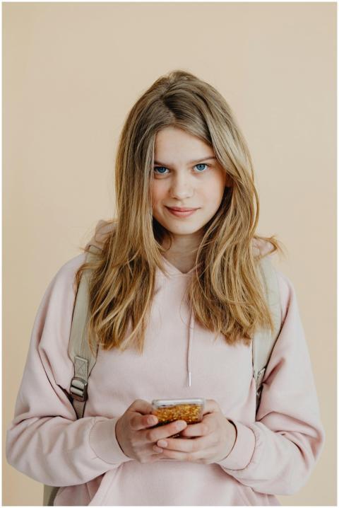 Blonde teenage girl holding mobile phone, wearing