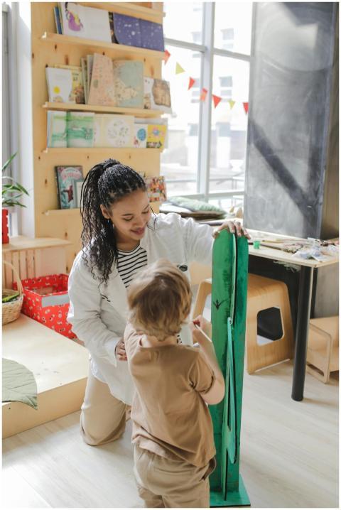 A teacher interacts with a child during an arts an