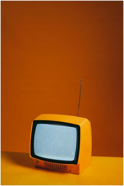 Vintage yellow TV set with antenna against a vibra