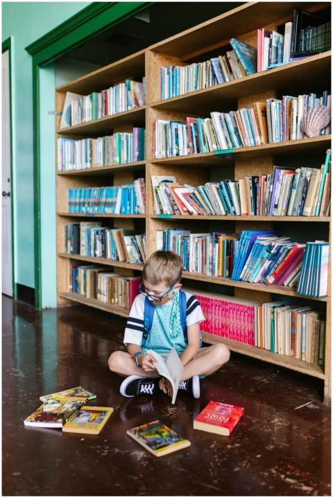 A child enjoys reading books inside a library, sur
