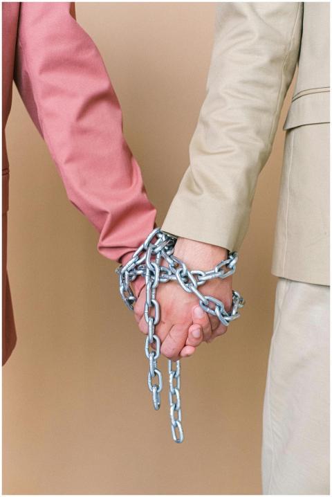 Close-up of two individuals holding hands bound by