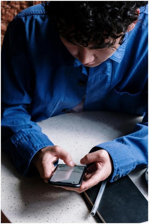 A young man in a blue shirt uses his smartphone in