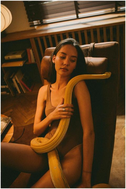 A woman in a brown outfit holds an albino python w