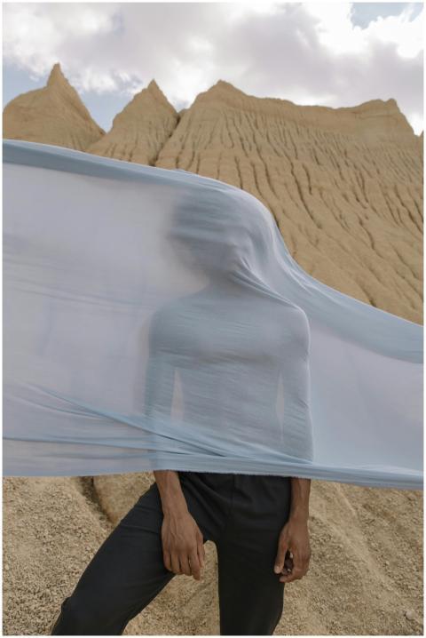 A man in a desert landscape obscured by flowing fa