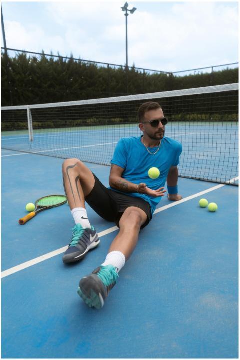 Adult male seated on tennis court with racket and