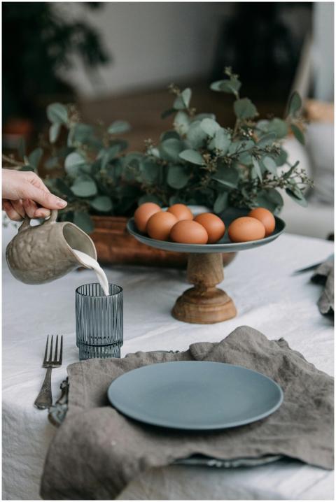 Rustic table setting with a hand pouring milk, sur