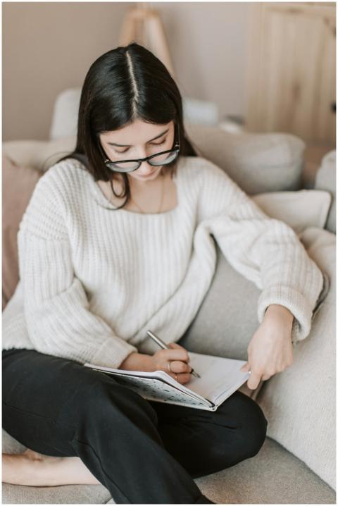 A young woman writes in a notebook while sitting c