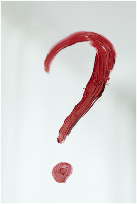 Close-up of a red painted question mark on a white
