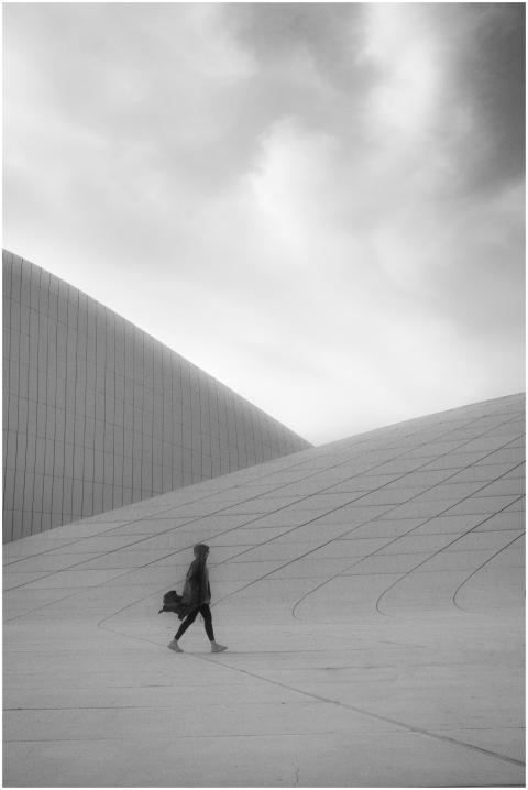 A woman walks by the modern architecture of Heydar