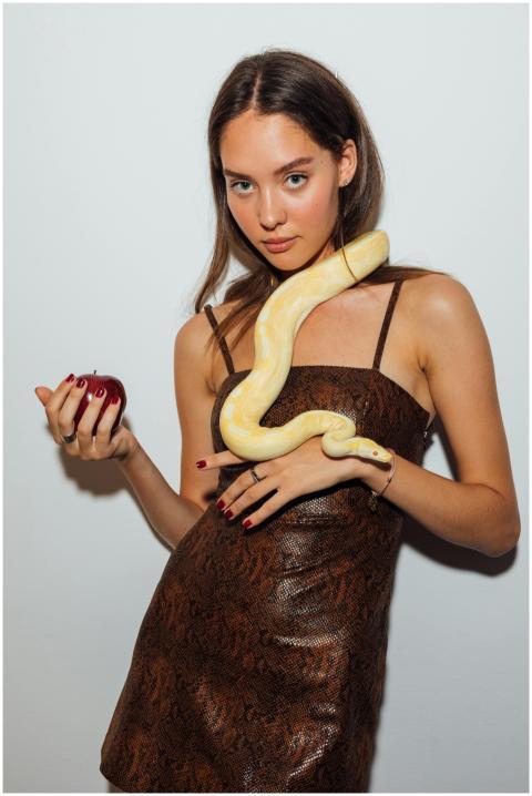 Woman with a snake around her neck holding a red a