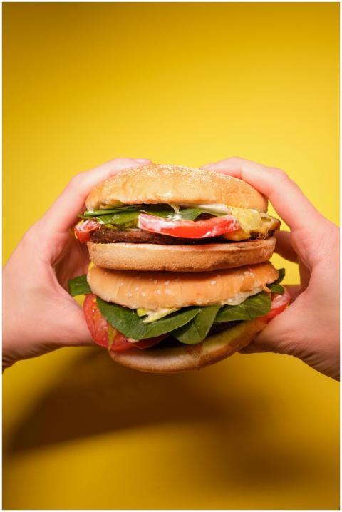 Crop anonymous person hands with burgers with toma