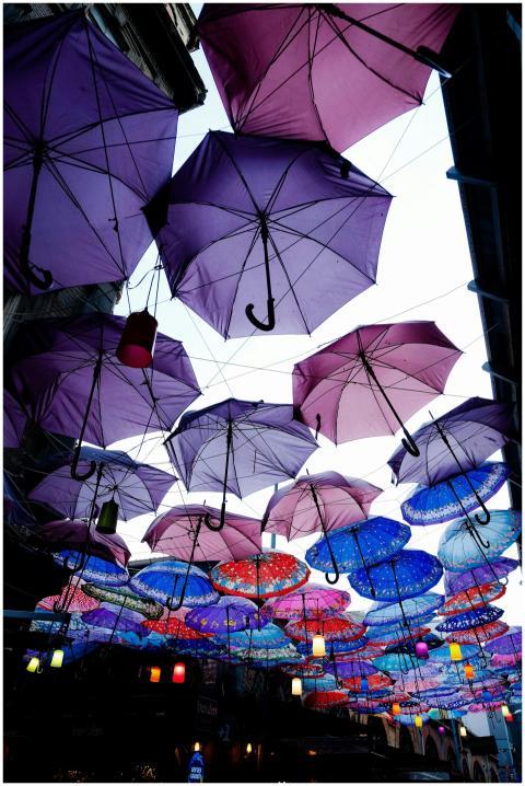 Colorful inverted umbrellas hang in a vibrant urba