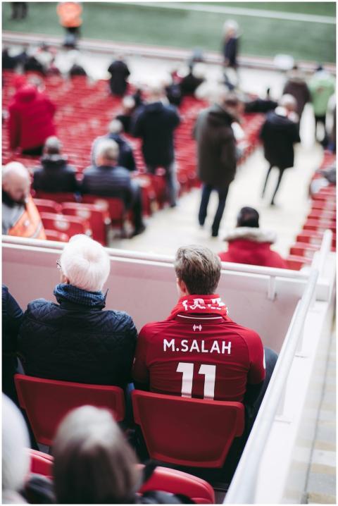Fans in red jerseys sit in a stadium, showcasing f