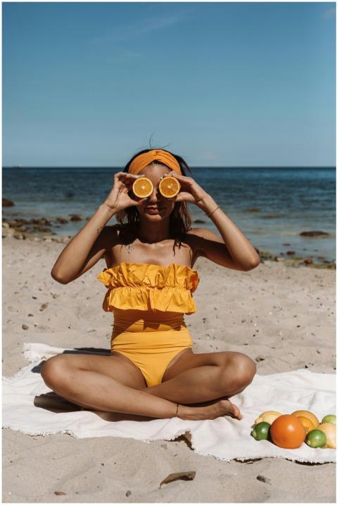 Woman in swimsuit holding orange slices on the bea
