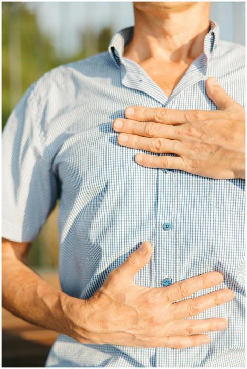 Close-up of a man in a blue shirt holding his ches