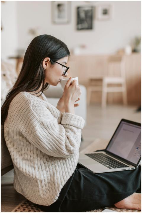 A woman in a cozy sweater works from home on a lap
