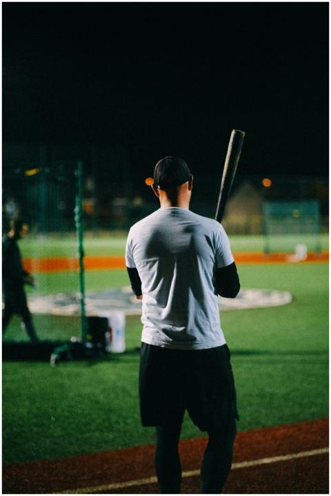 A baseball player stands with a bat on a sports fi